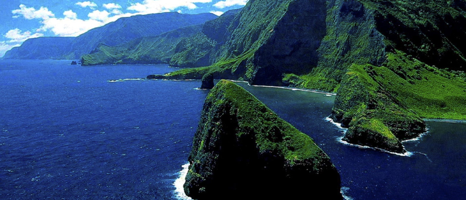 Green cliffs overlooking a blue ocean bay.